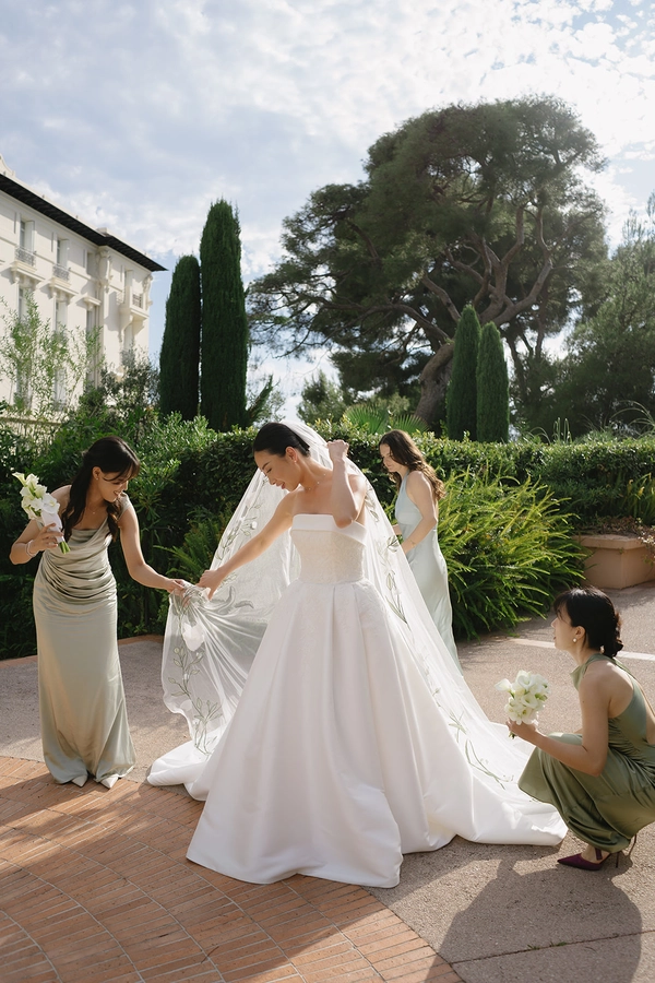 Bride putting on her veil with bridesmaids in the sun at Grand-Hôtel du Cap-Ferrat, modern documentary wedding in French Riviera